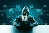 Hacker con cappuccio davanti a un computer durante un attacco phishing con email fraudolente e rete digitale globale sullo sfondo.